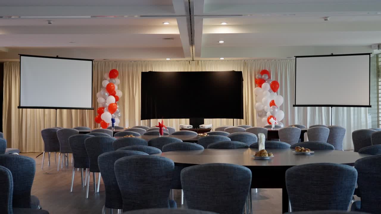 Corporate event setup with chairs, screens, and balloons