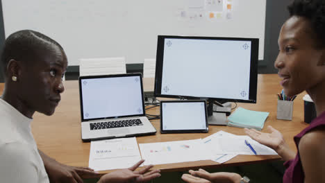 african american businesswomen talking and using technology, with copy space on screens, slow motion