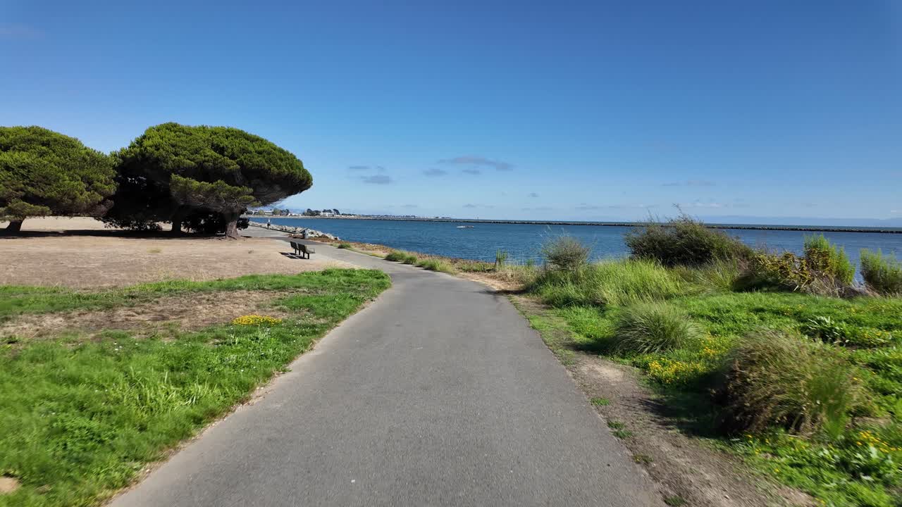 Camera moves forward on Encinal Beach trail in Alameda, California, with waterfront views of the bay, sand, and horizon, perfect for lifestyle, landscape, and environmental footage