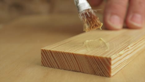 a block of wood having glue applied to it by a carpenter in slow motion