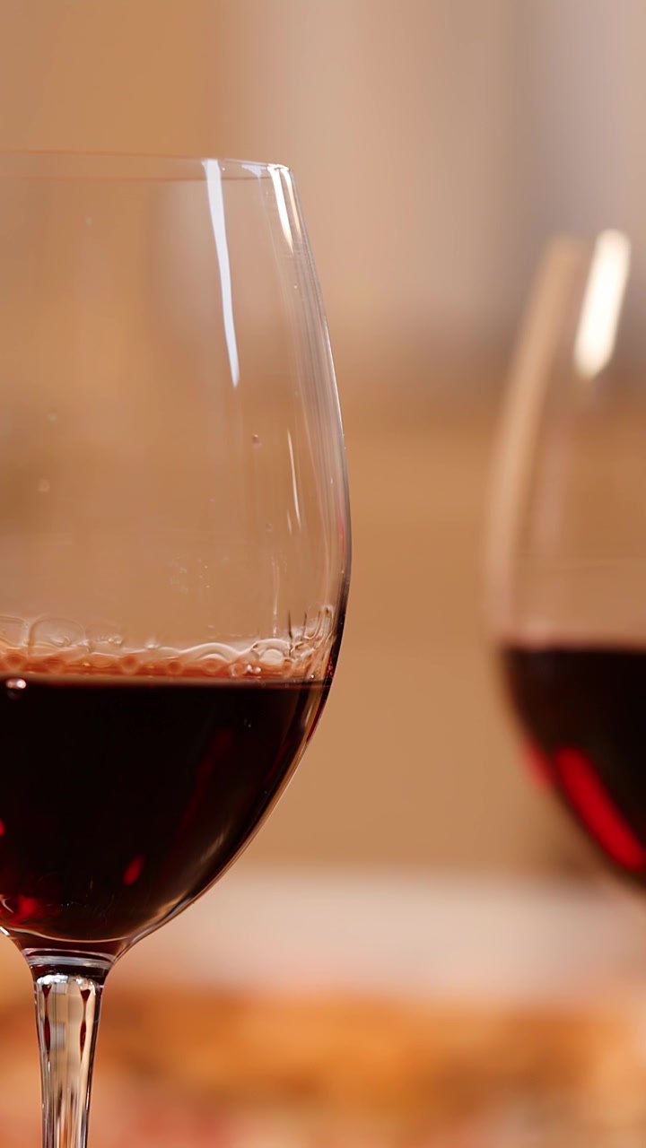 Una mano solleva un bicchiere di vino rosso da un tavolo durante una cena italiana