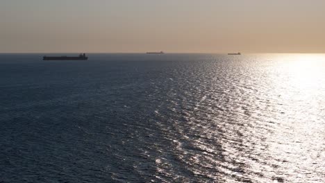 Three-tanker-container-ships-wait-outside-on-horizon-of-Caribbean-sea-at-sunset