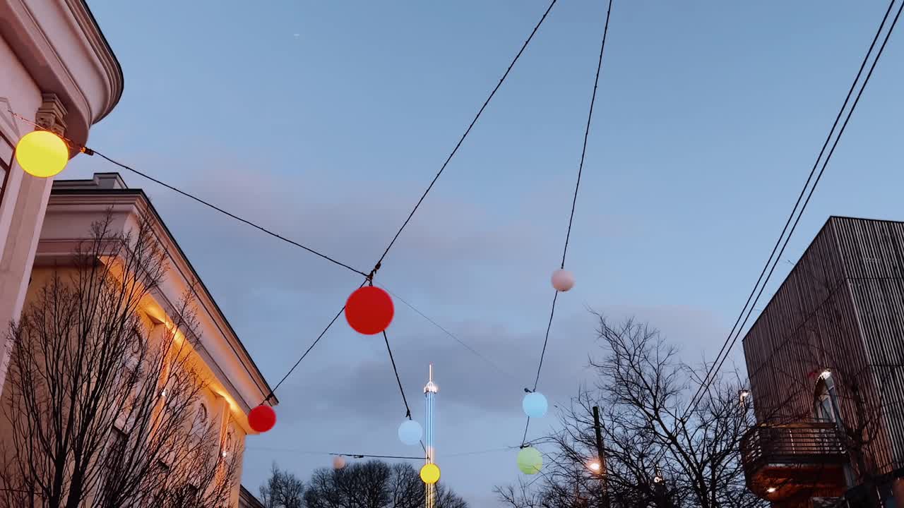 Colorful hanging lights over a city street at dusk in Vienna, Austria
