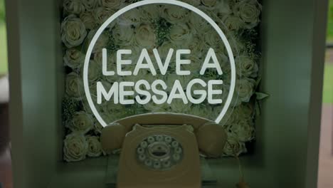 vintage rotary phone with a "leave a message" sign, set against a backdrop of white roses