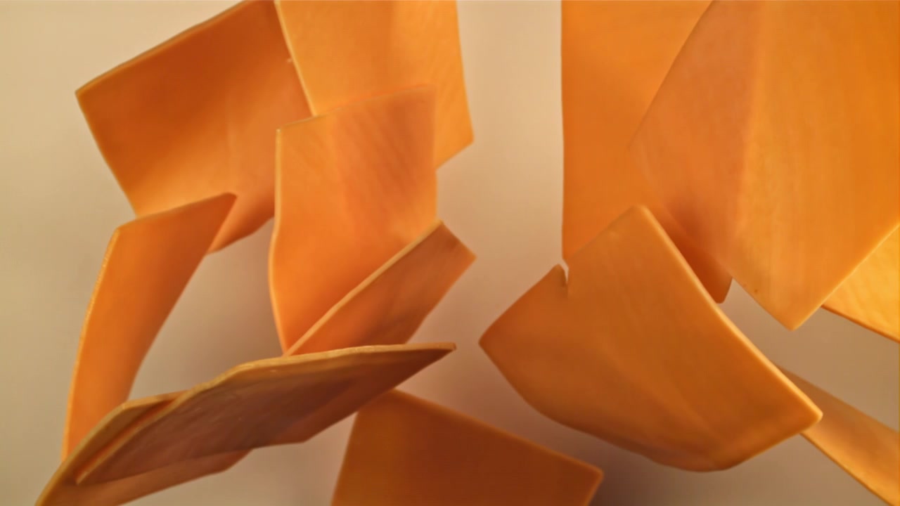 Fette di formaggio quadrate arancioni che cadono su sfondo bianco