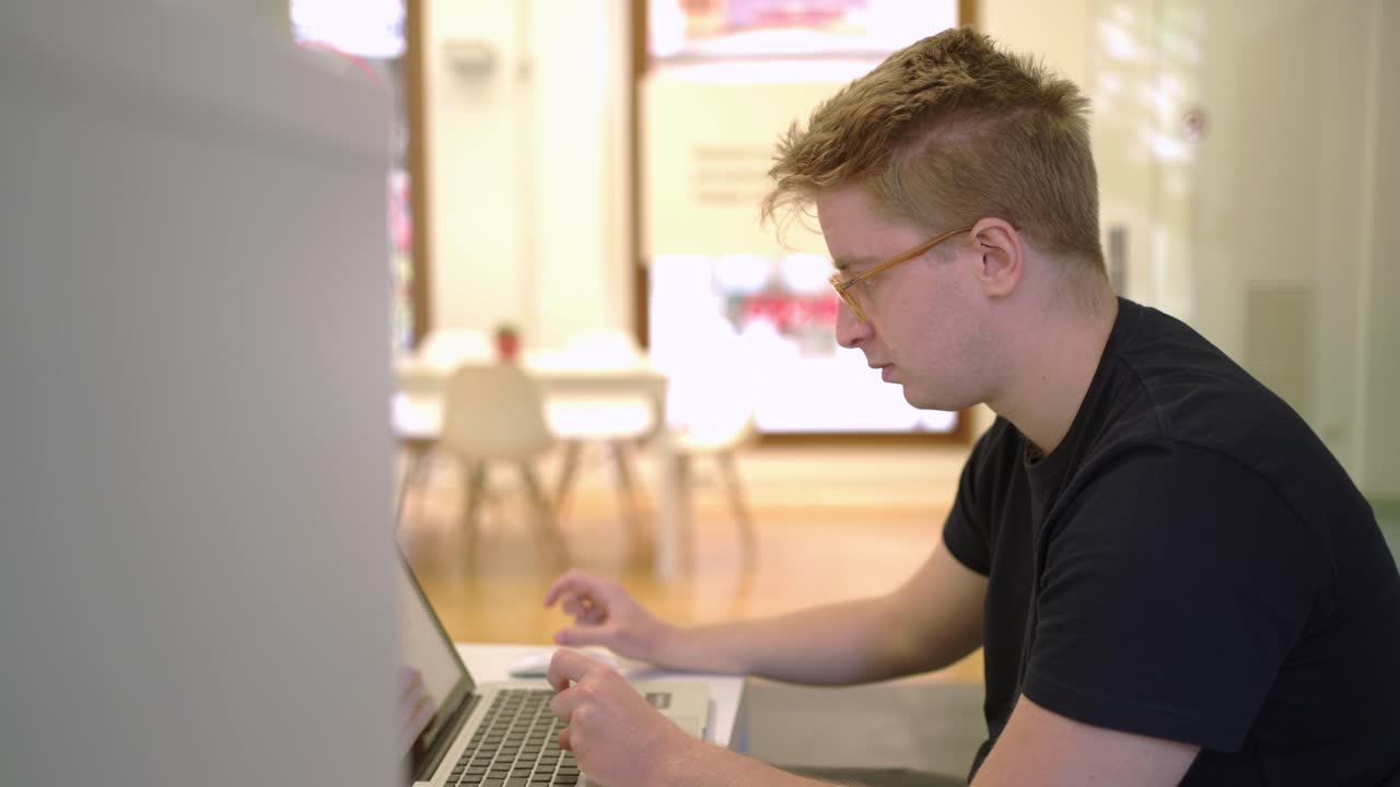 Man in eyeglasses working on laptop in office