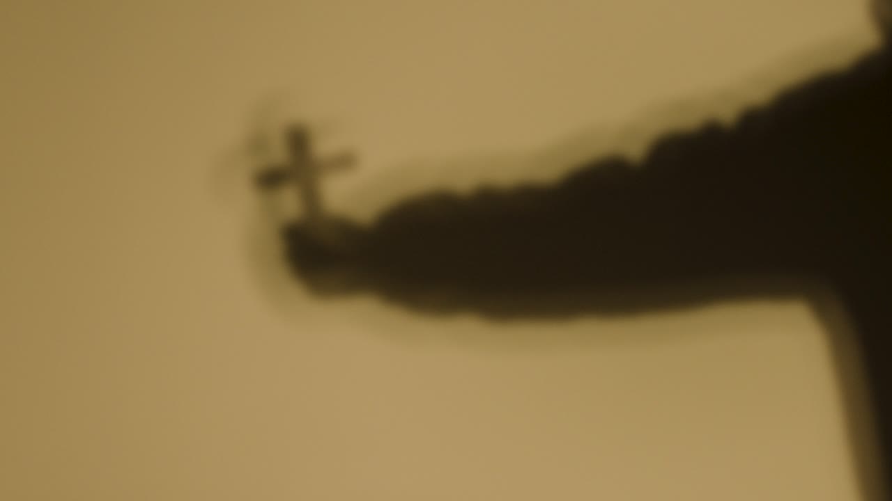 노란색 배경에 십자가를 들고 있는 사람의 그림자가 있는 종교적인 개념