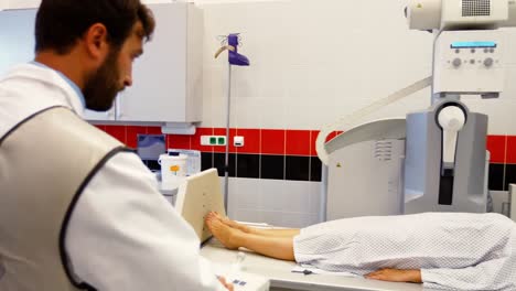 male doctor sets up the machine to x-ray a female patient
