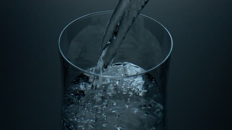 pure water pouring cup closeup. refreshing liquid bubbling filling glass jug