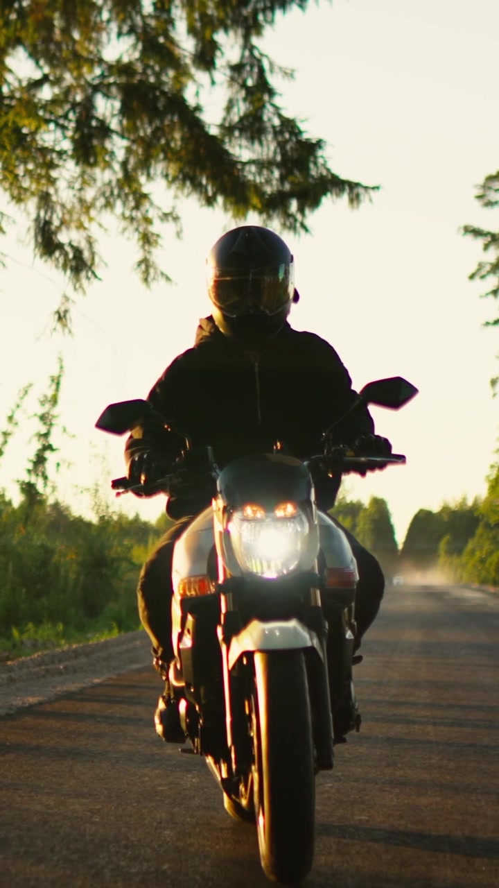 Motociclista in moto su una strada di campagna al tramonto