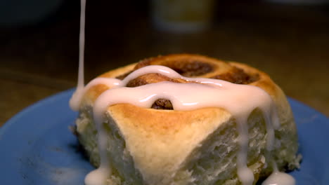 a person putting an icing in the delicious cinnamon rolls on the plate - closeup shot