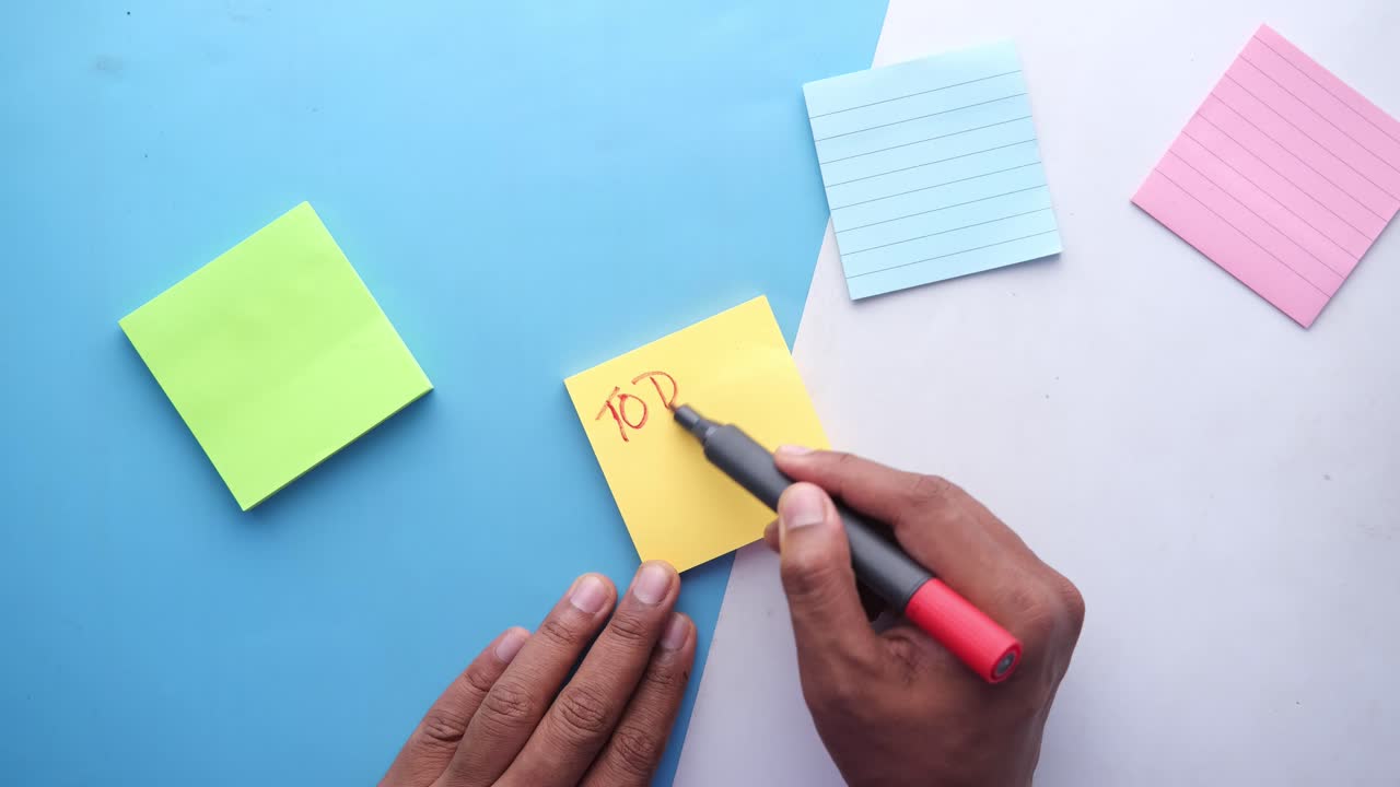 Person writing a to-do list on sticky notes