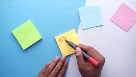 person writing a to-do list on sticky notes