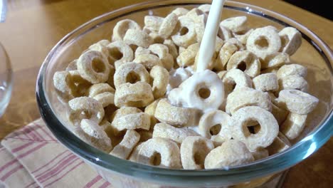copos de avena crujientes en un tazón para un delicioso desayuno matutino con leche. cámara lenta con toma de seguimiento de rotación.