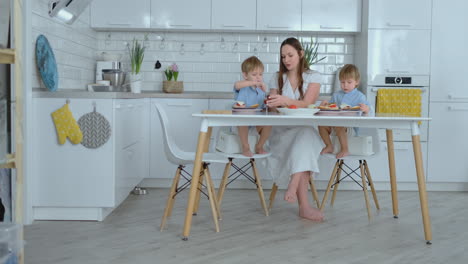 two young boys children help mom in the kitchen prepare burgers slicing vegetables cheese and sausages