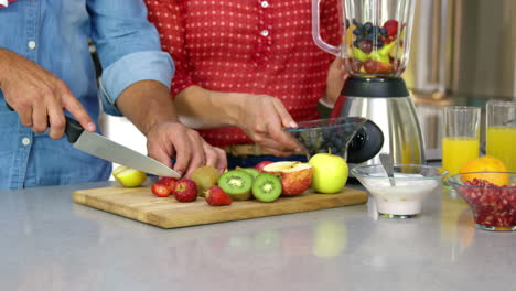 pareja preparando jugo de frutas en la cocina