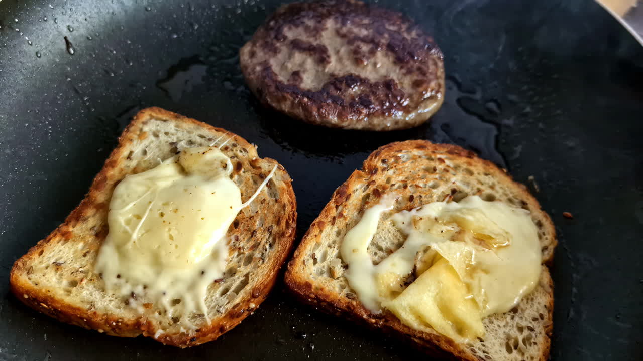 a breakfast sandwich with cheese and beef on a frying pan with oil, a home-cooked dish