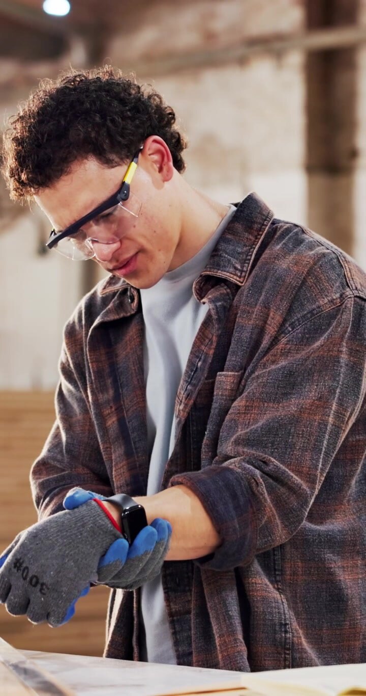 Young Carpenter Putting on Protective Gloves in Workshop