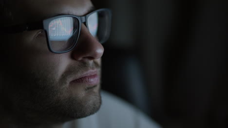 primer plano de las gafas hombre. inversor viendo el cambio de la bolsa de valores en la pantalla del portátil. comerciante superior mira gráficos corriendo análisis de datos para hacer la mejor venta. lleno de pantallas y estadísticas