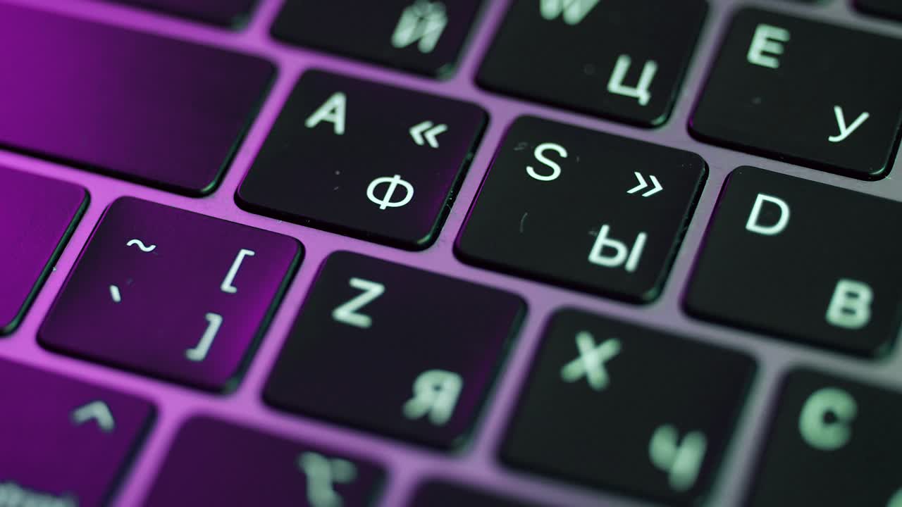 Close-up of a laptop keyboard with purple light