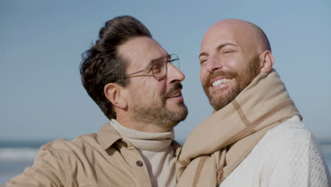 close up of a happy gay couple kissing and hugging on the beach