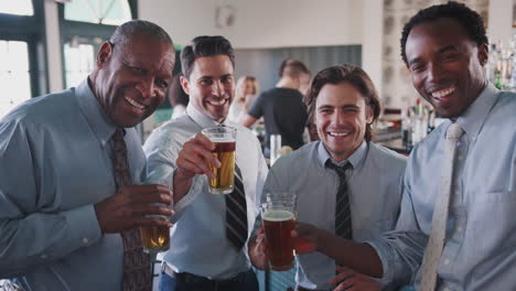 Portrait-Of-Businessmen-Meeting-For-After-Works-Drinks-In-Bar-Making-A-Toast-At-Camera