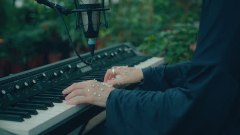 female musician playing song on keyboard in indoor garden