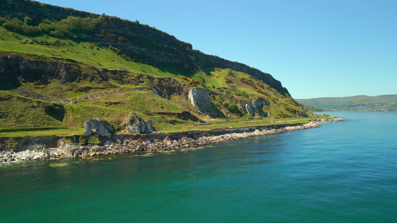 Wide, reversing aerial video of Madman's Window on the Causeway Coastal Route in County Antrim, Northern Ireland, UK, on a bright and sunny day. Filmed in 4K, 60FPS and with Rec709 color.