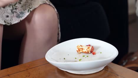 woman eating tasty appetizer food as a snack from coffee table while sitting on a couch, pita bread chips with hummus and diced tomatoes, no faces