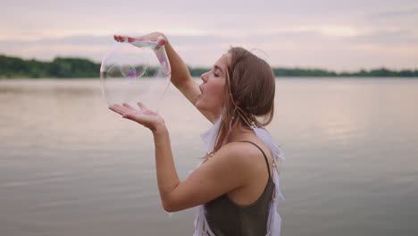 a young girl artist shows magic tricks using soap bubbles. create soap bubbles in your hands and inflate them location theatrical circus show at sunset