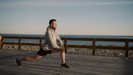 man stretching on a wooden pier by the sea