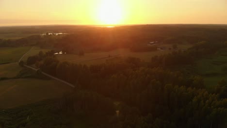 puesta de sol dorada sobre el paisaje de la agricultura y el bosque, vista aérea