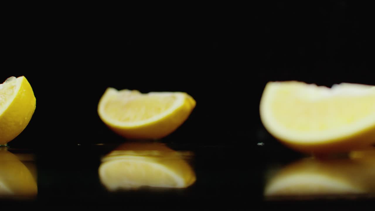 un zumo de limón amarillo cortado cayendo sobre un vaso con salpicaduras de agua en cámara lenta sobre un fondo oscuro.