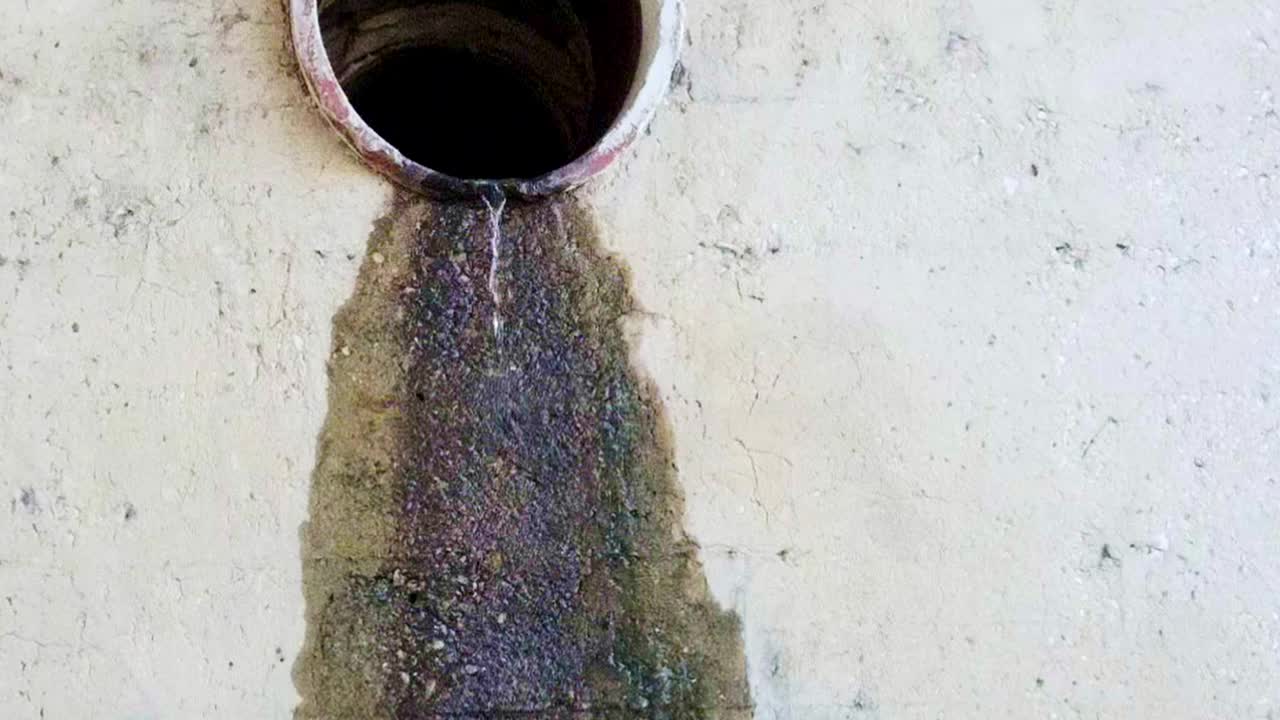 Road drainage coming dripping out of a sewer pipe and running down the wall Slow motion camera zooming out