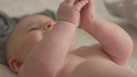 closeup of baby's hands, upper body, newborn in playful mood dressing white bedroom