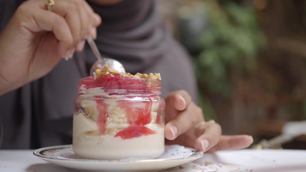 Gros plan d'une personne mangeant un dessert étagé dans un bocal
