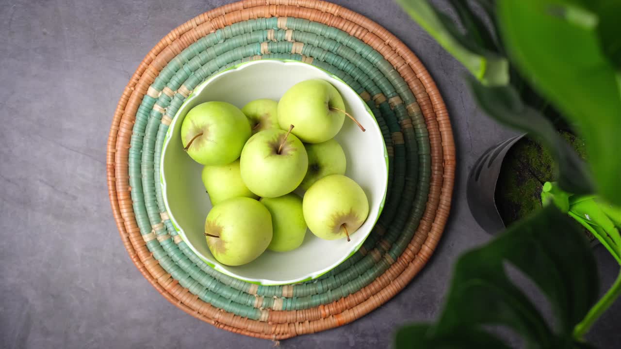 manzanas verdes en un tazón en un placemat de mimbre