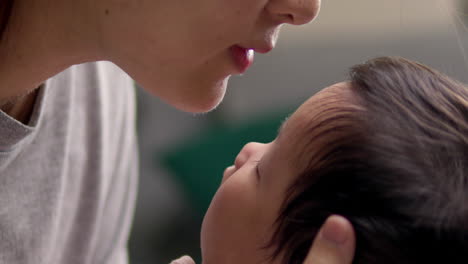 새로 태어난 아기의 이마에 부드러운 키스를 는 어머니는 아기를 부드럽게 품에 안고 있습니다.