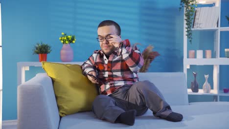 un joven enano discapacitado descansando en el sofá en casa y mirando su teléfono inteligente.