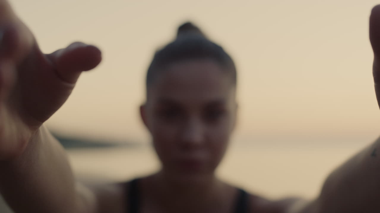 mujer en forma sostiene las manos practicando yoga en la playa de cerca. chica haciendo gimnasia