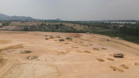 Heavy-machinery-working-on-new-Construction-site-on-Countryside-field,-Aerial-tracking-shot
