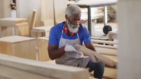 carpintero afroamericano buscando y eligiendo un tablón de madera en una carpintería