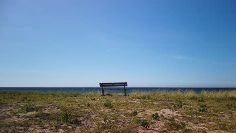 Banco-Solitario-Con-Vistas-Al-Tranquilo-Mar-Báltico-En-La-Costa-Irevik-De-Gotland,-Cielo-Azul-Claro