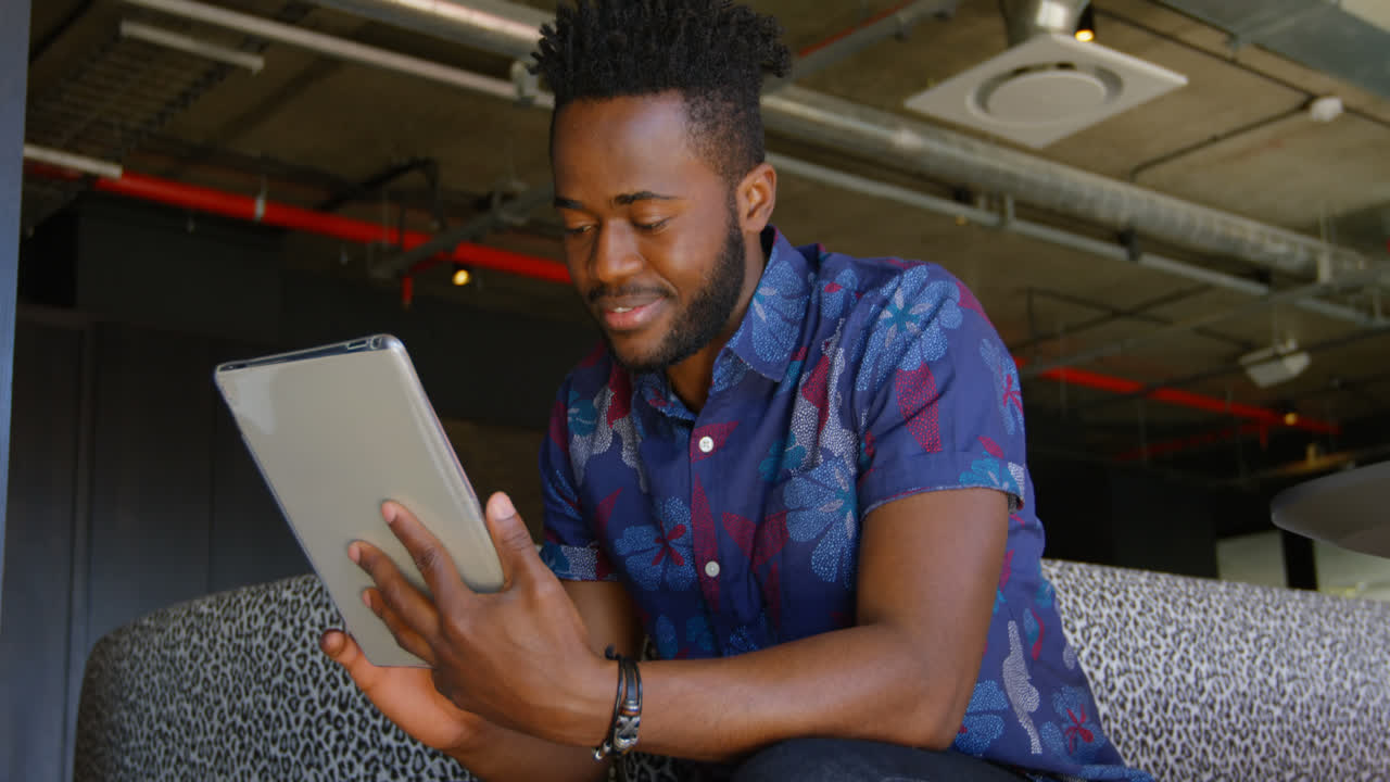 Front view of young black businessman working on digital tablet in a modern office 4k