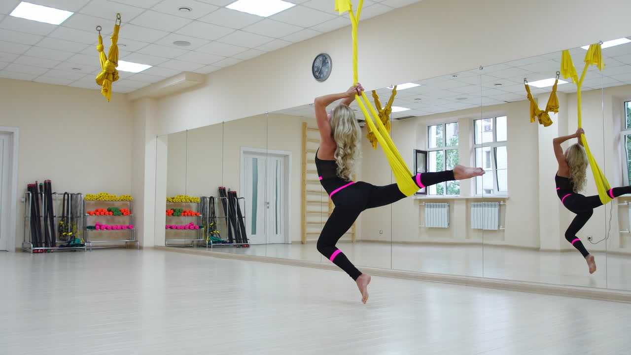 deporte concepto de estilo de vida saludable. espacio de copia. ajuste mujer joven bonita usando ropa deportiva haciendo yoga volar ejercicios de estiramiento en entrenamiento de fitness sala de clase de gimnasio blanco loft.