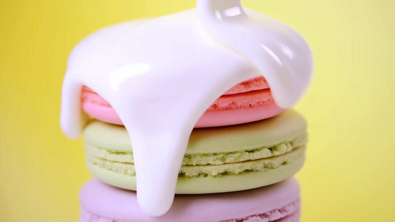 Pastel Macarons With Glossy Cream Being Poured Over Colorful Stack Against Bright Yellow Backdrop, Playful