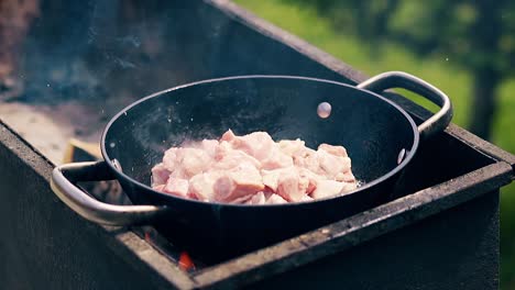 close-up slow motion pork meat is fried in a saucepan on charcoal