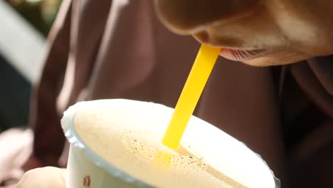 mujer bebiendo jugo con paja de plástico