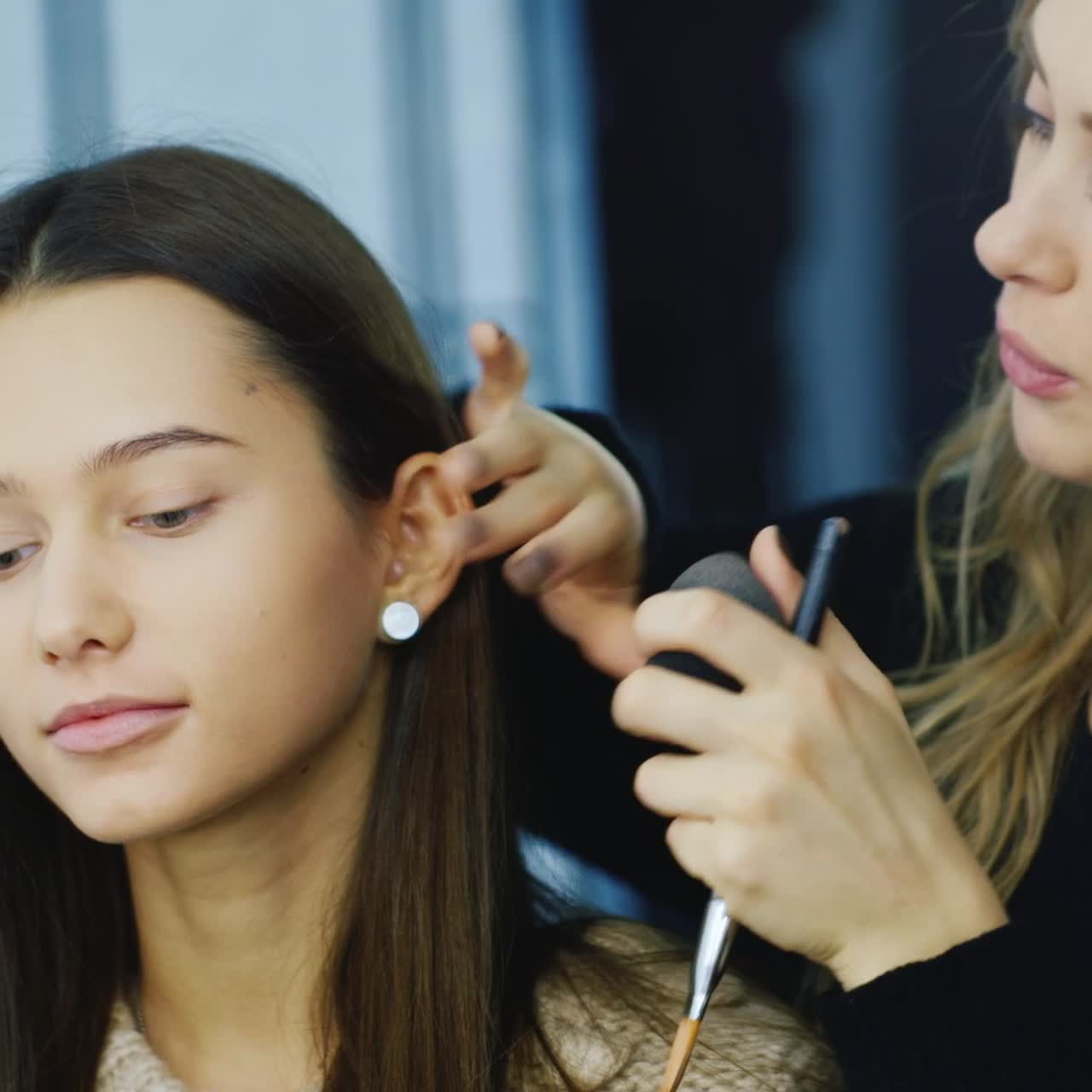Una truccatrice trucca una giovane donna in studio 3