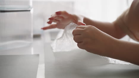 female hands press on protective film popping bubbles